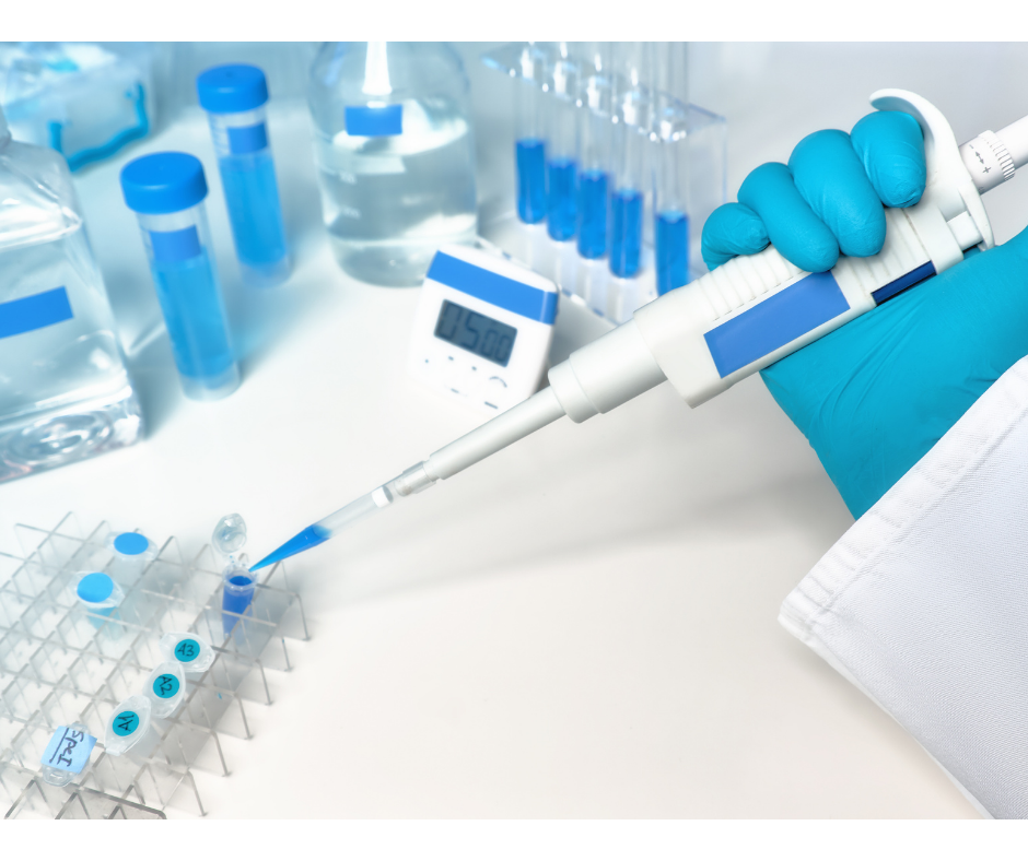Pipeta de laboratorio depositando una muestra en una gradilla, junto a tubos y reactivos